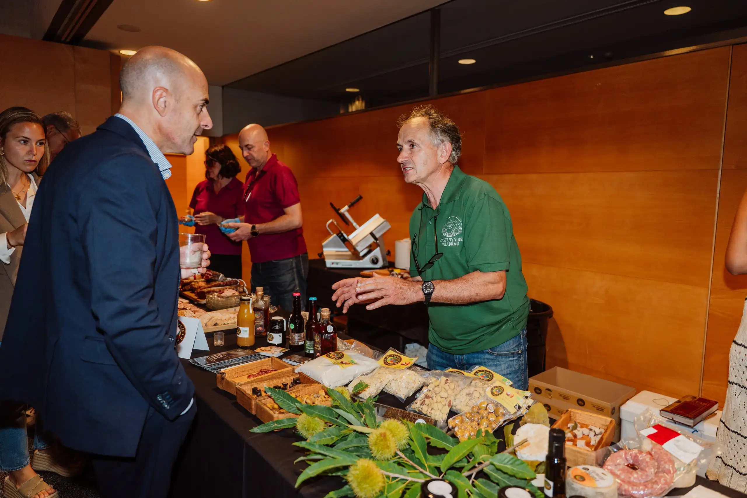 Dos homes conversen al costat d’una parada de tast durant la gala