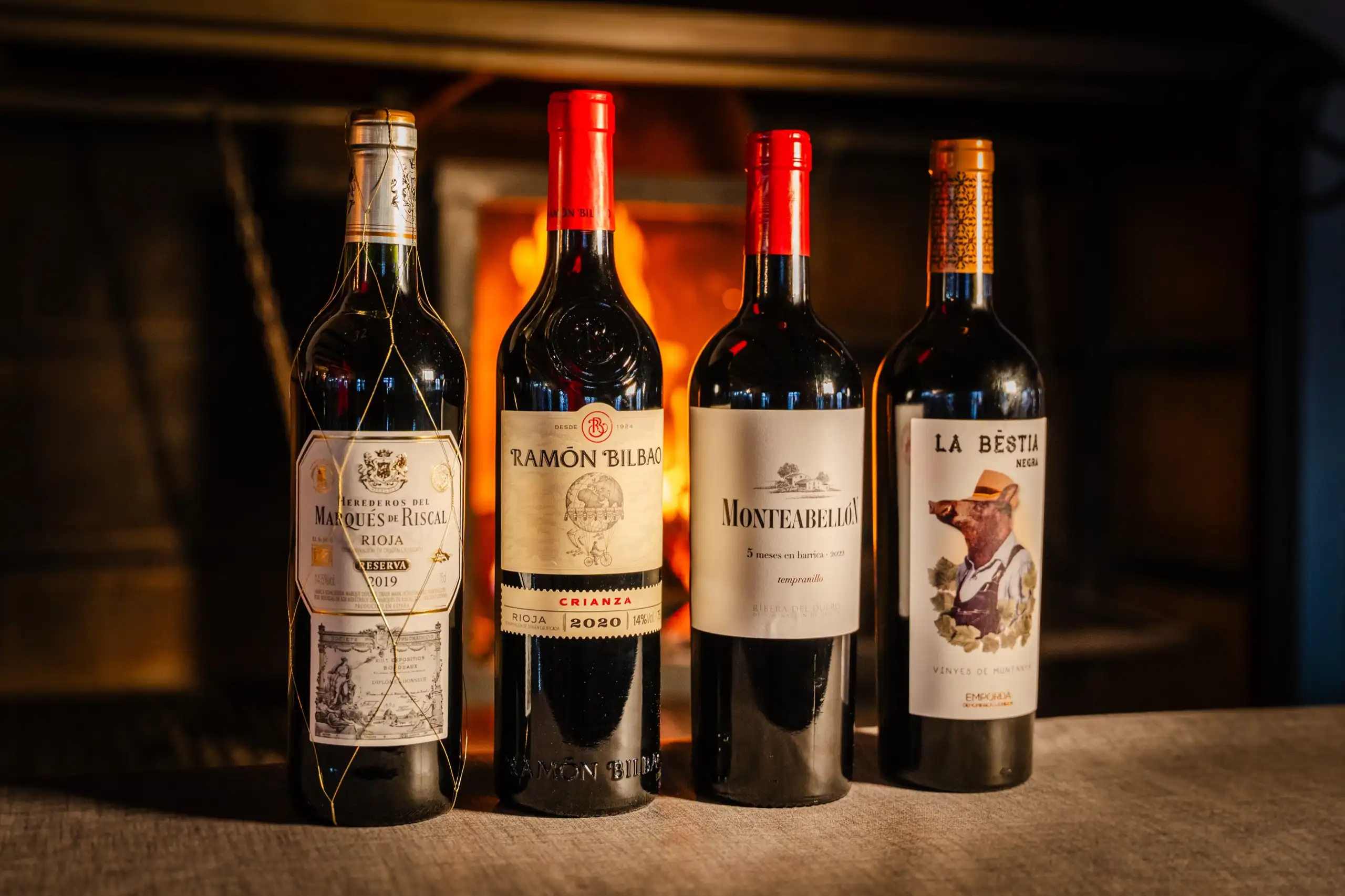 Cuatro botellas de vino tinto frente a la chimenea del restaurante