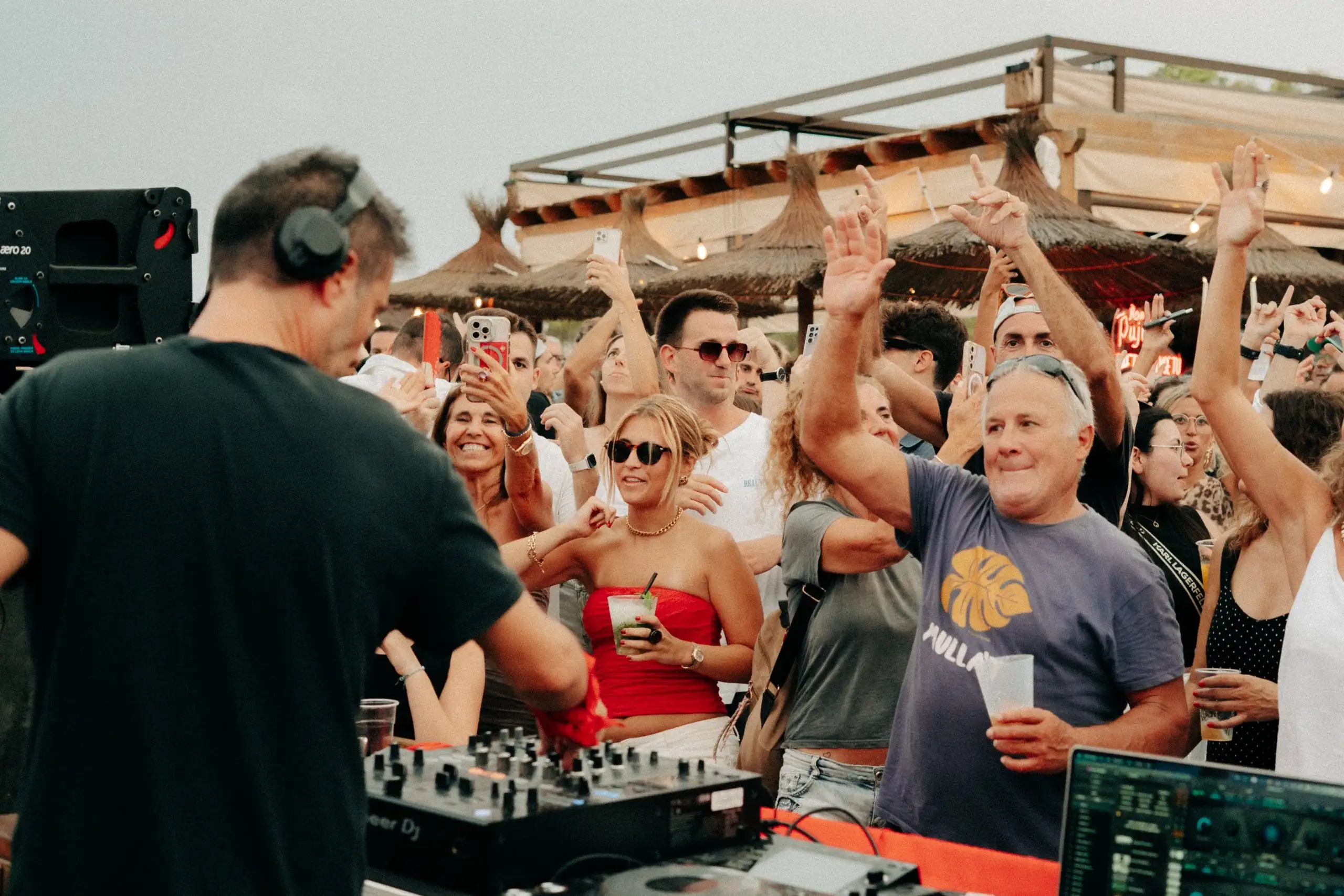 El DJ punxa a la pista mentre el públic aixeca els braços